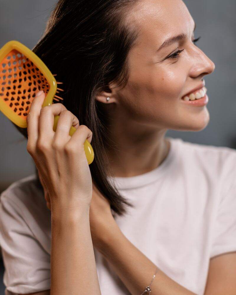 Smiling woman brushing her healthy-looking hair